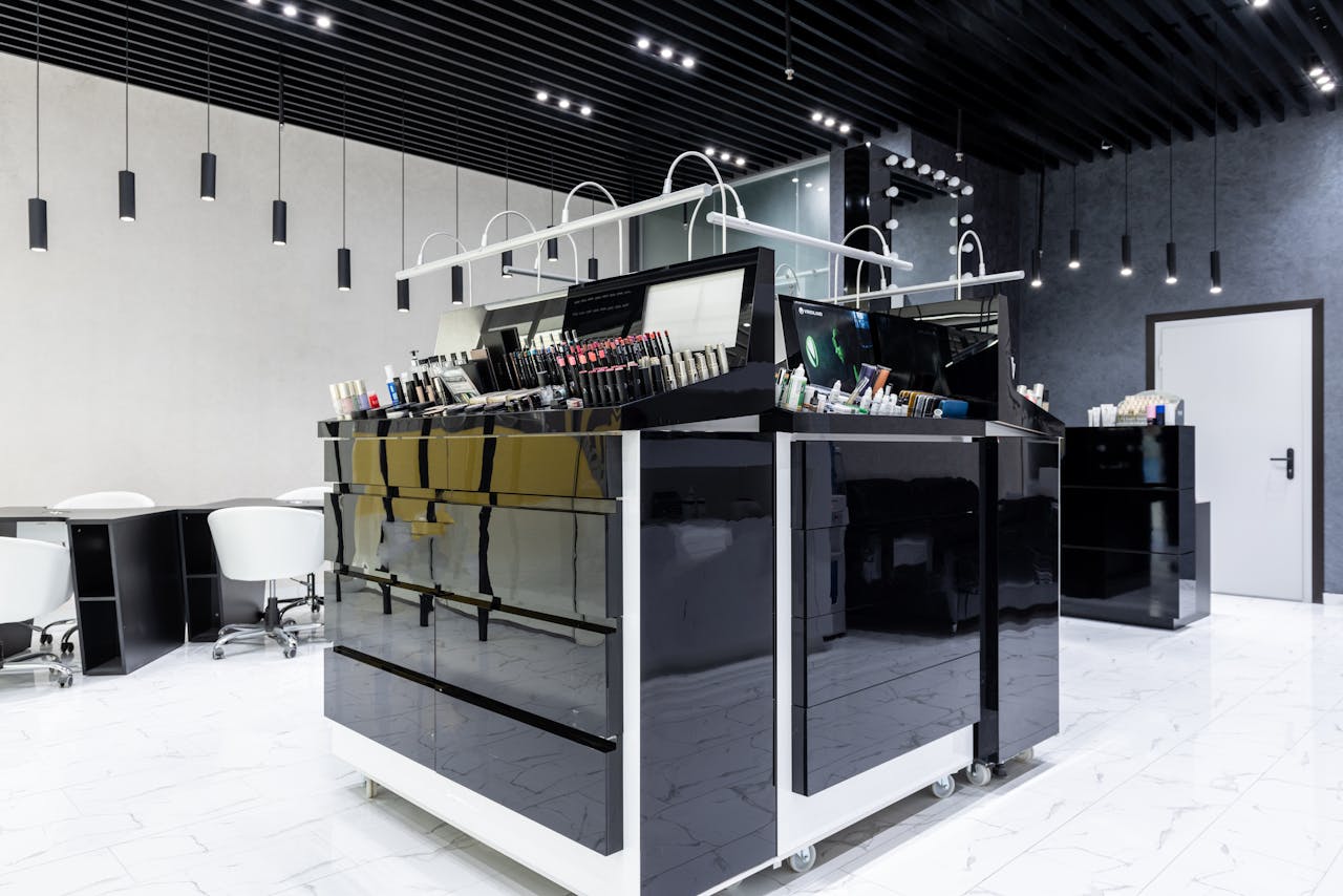 Sleek makeup store interior featuring black glossy cabinets, chairs, and ample lighting.